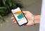 Eine Hand mit silbernem Armband hält ein Smartphone, auf dem ein LinkedIn-Post des AFgE-Accounts zu sehen ist. Der Post zeigt ein Event-Motiv in Orange und Türkis mit dem Text "HEP-Tag 2025, 05/08/25, Berlin" sowie einer türkisen Sprechblase mit Beschreibungstext. Darunter ist der Begleittext "Tag der Heilerziehungspflege 2025 in Berlin. Alles zum Programm." mit einem "Mehr erfahren"-Button zu sehen. Im Hintergrund sind unscharf grüne Pflanzen zu sehen.
